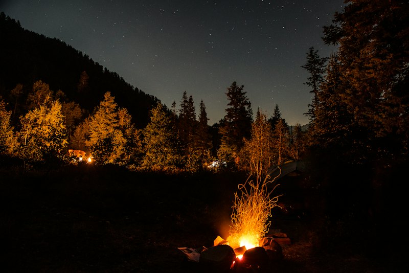 A campfire burning under a sky full of stars